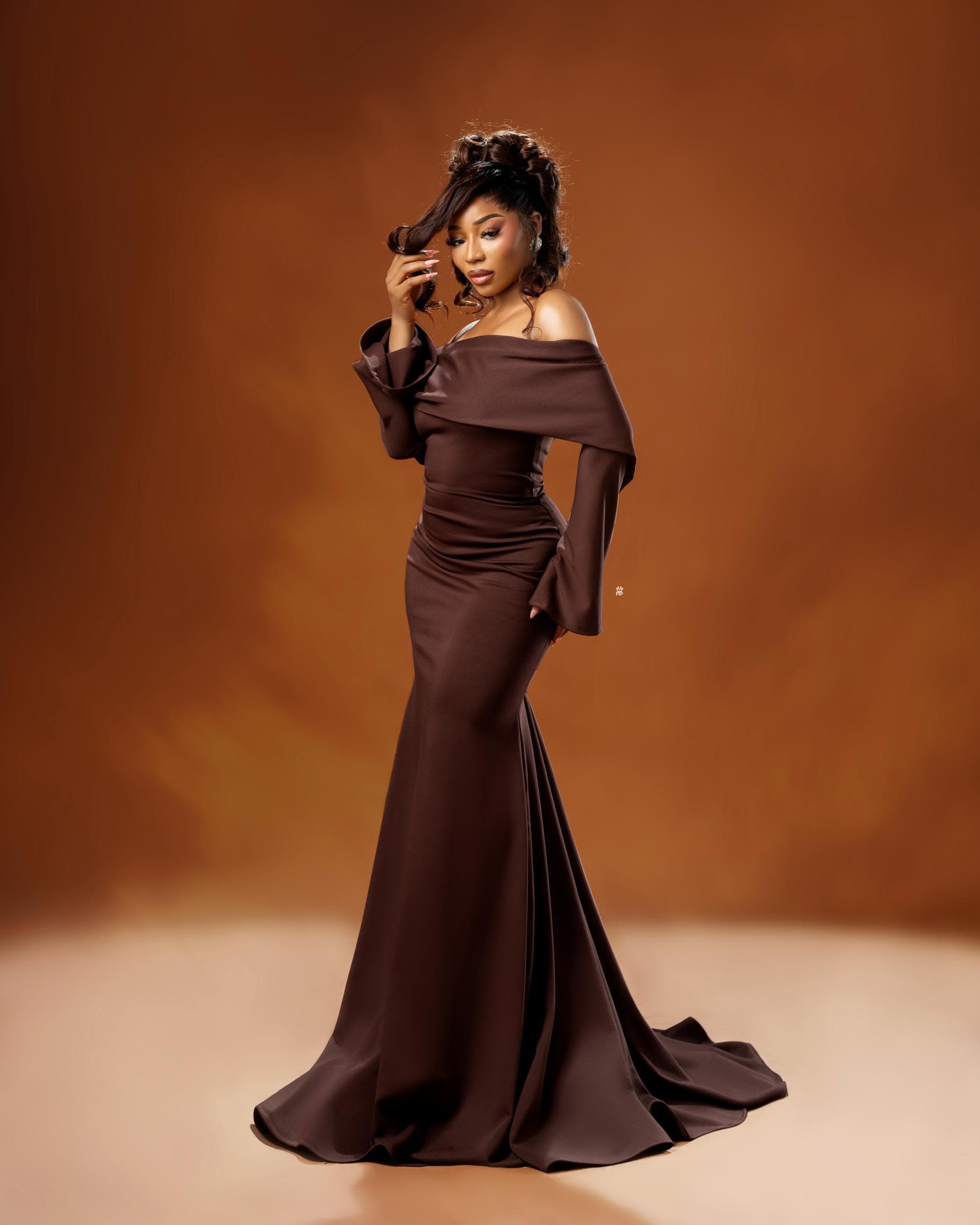 Model in a tailored brown off-shoulder evening gown by Luwa by Design